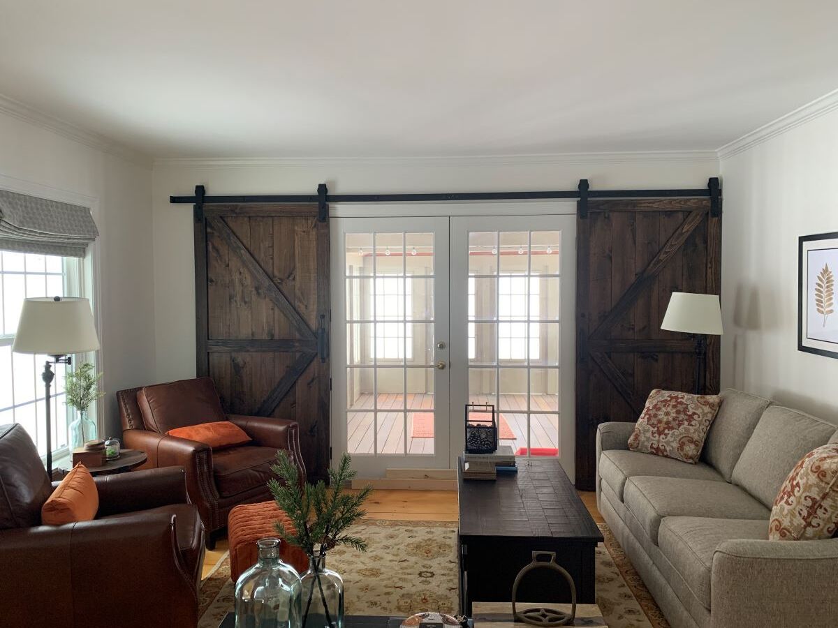 A living room with a couch , chairs , coffee table and sliding barn doors.