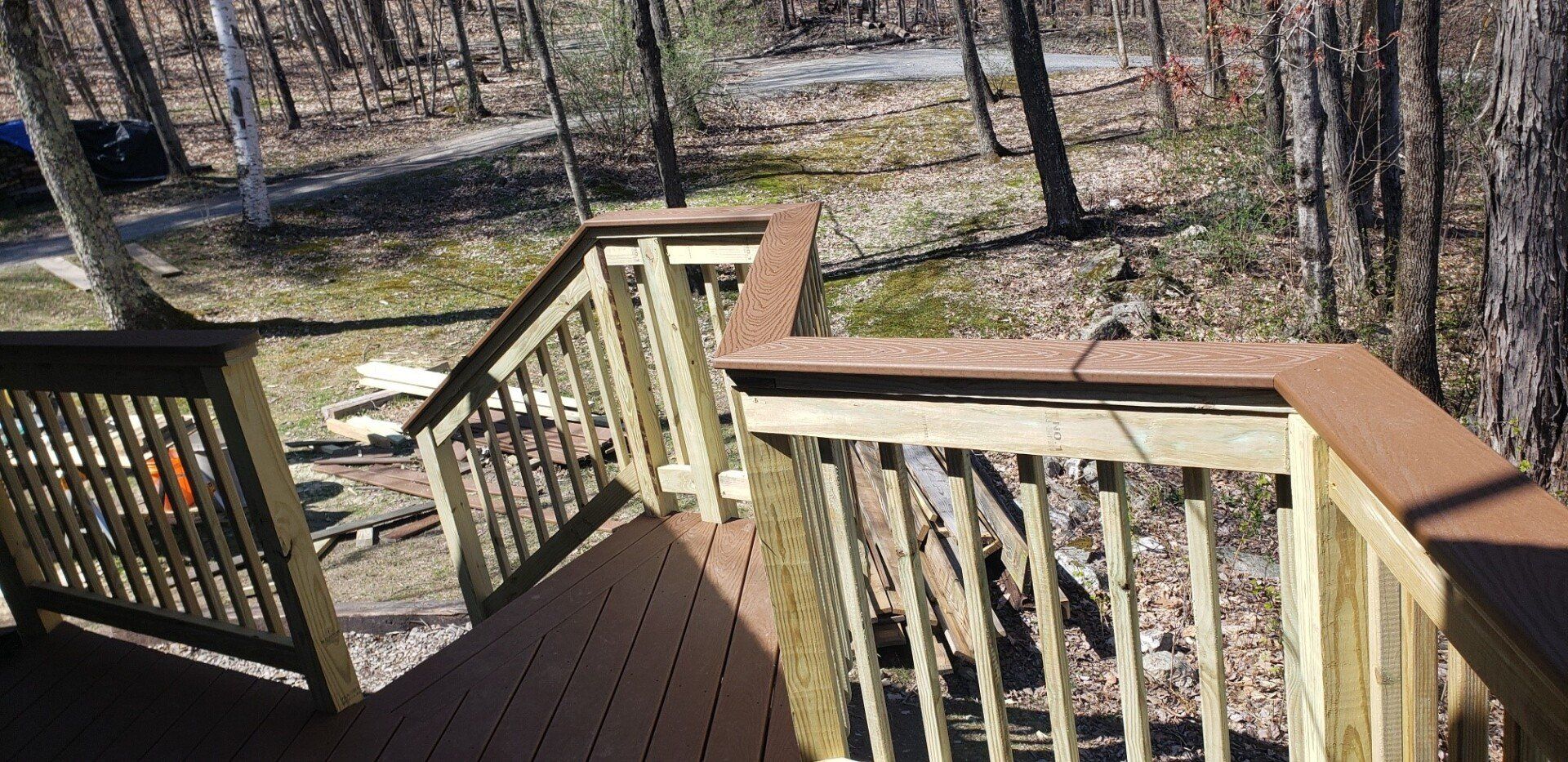 A wooden deck with stairs leading up to a forest.
