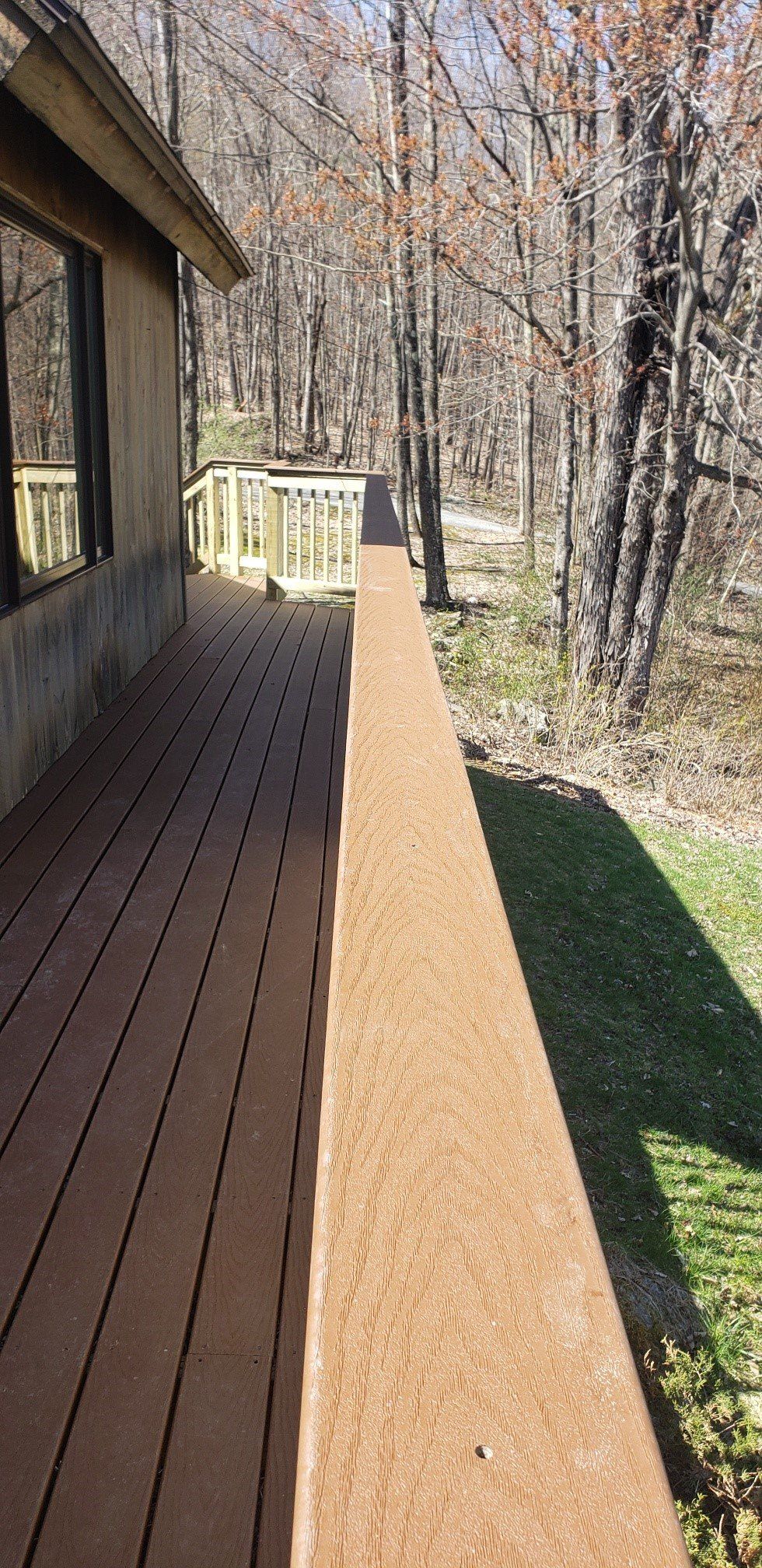 A long wooden deck leading to a house in the woods.