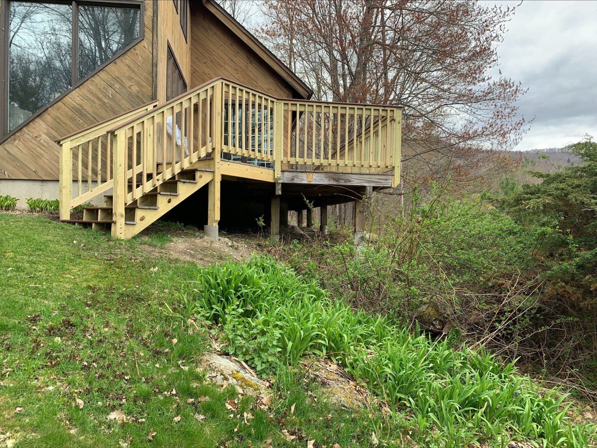 A house with a wooden deck and stairs on the side of it.