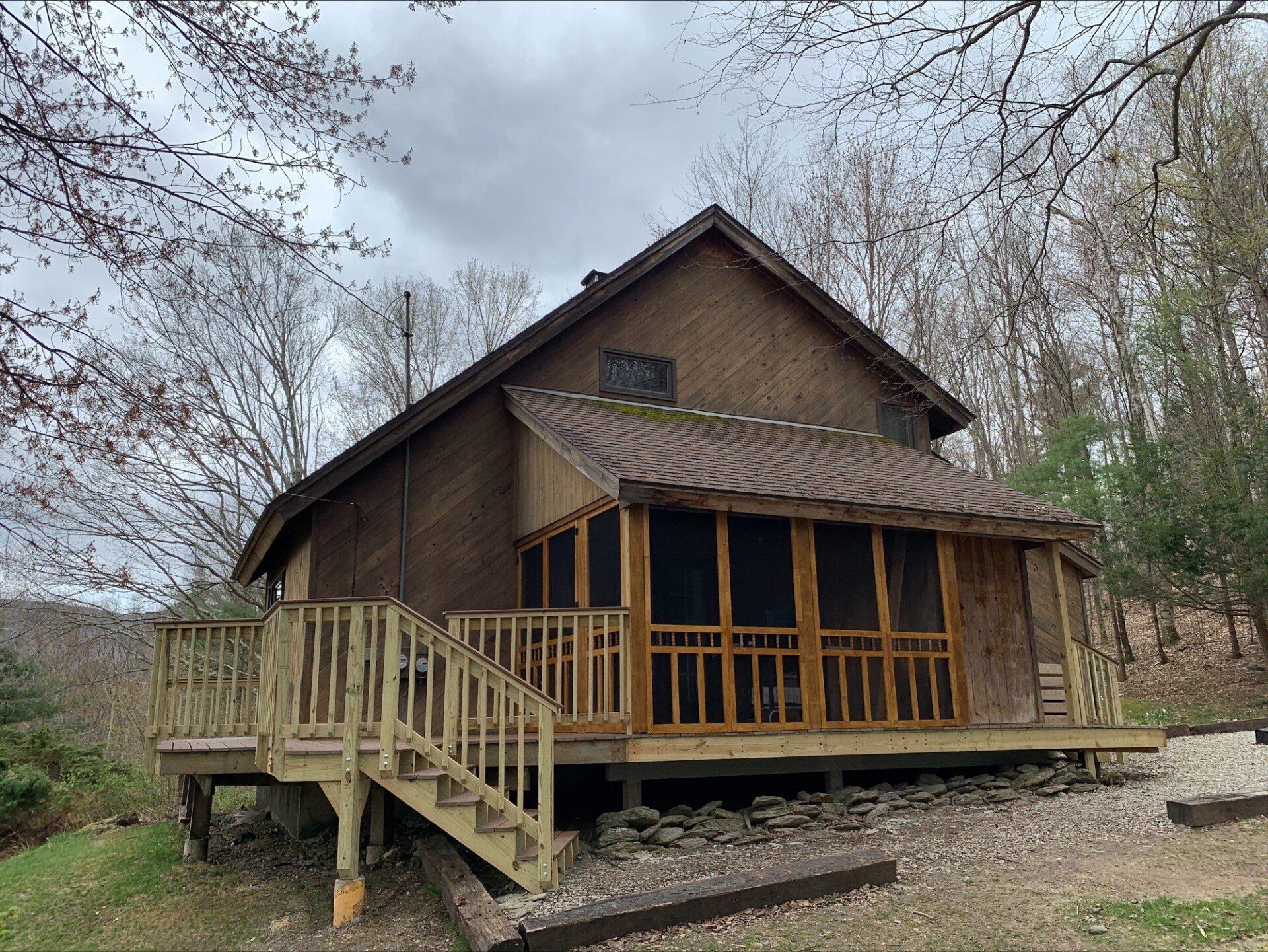A small house with a screened in porch and stairs.