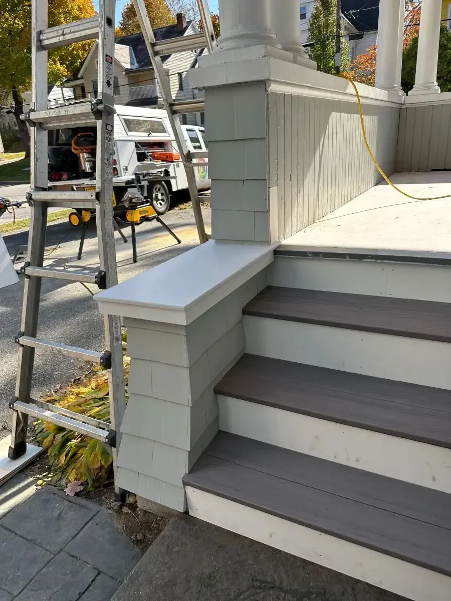 A ladder is sitting on top of a porch next to a set of stairs.