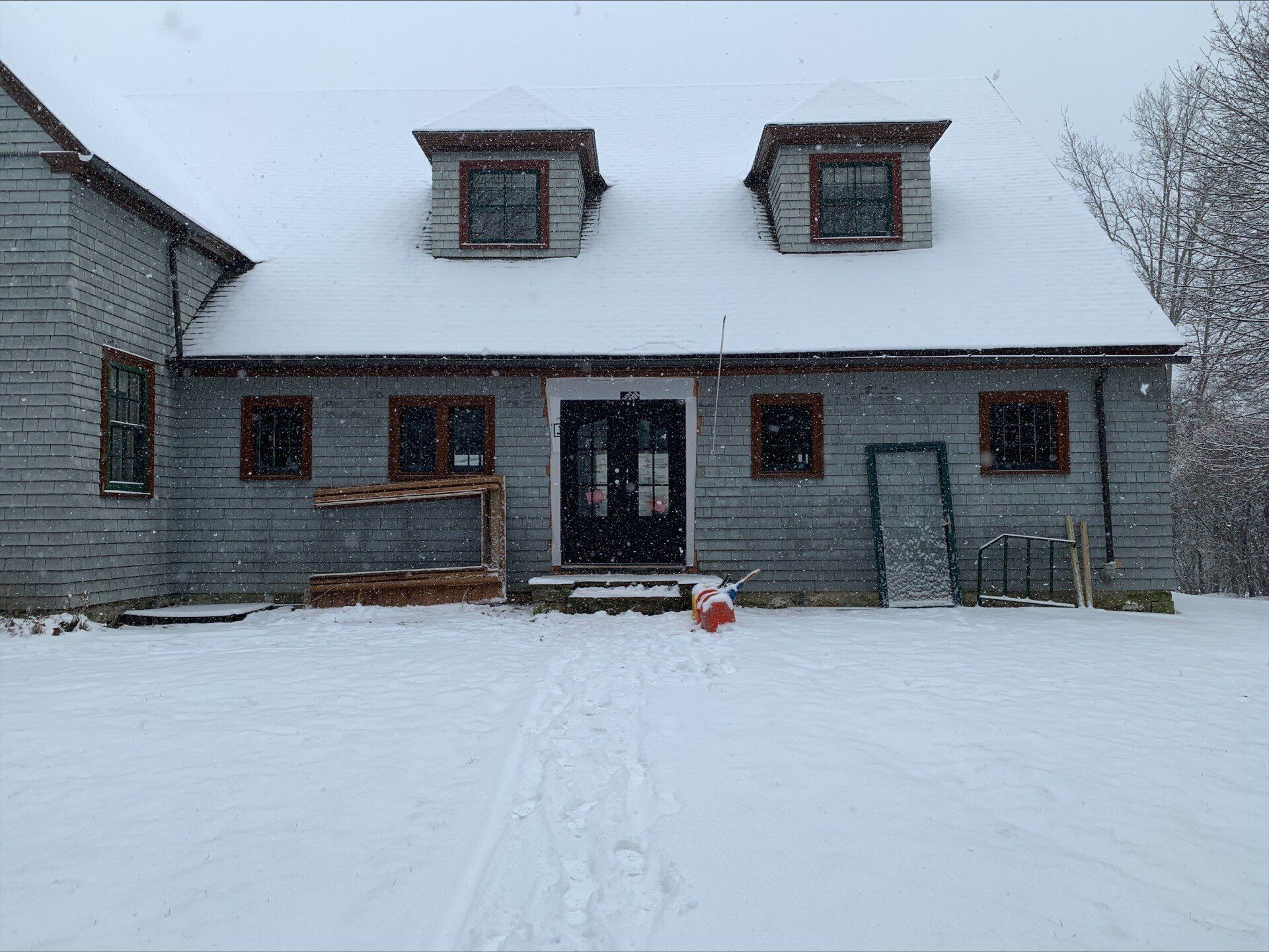 A house is covered in snow and there is a path leading to it.