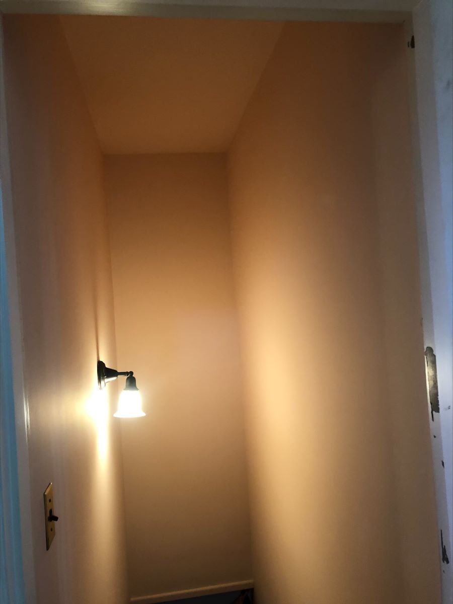 A narrow hallway with a light on the wall