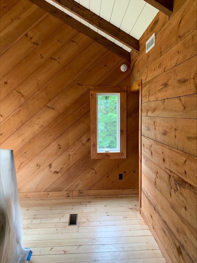 An empty room with wood paneling and a window