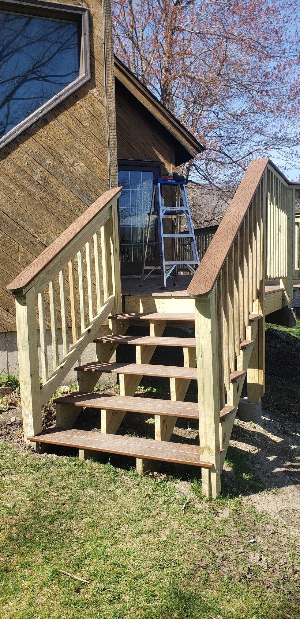A wooden deck with stairs leading up to a house.