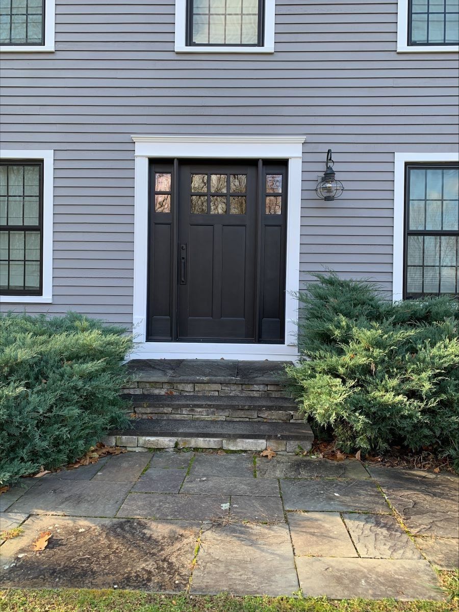 The front door of a house with a black door and white trim.