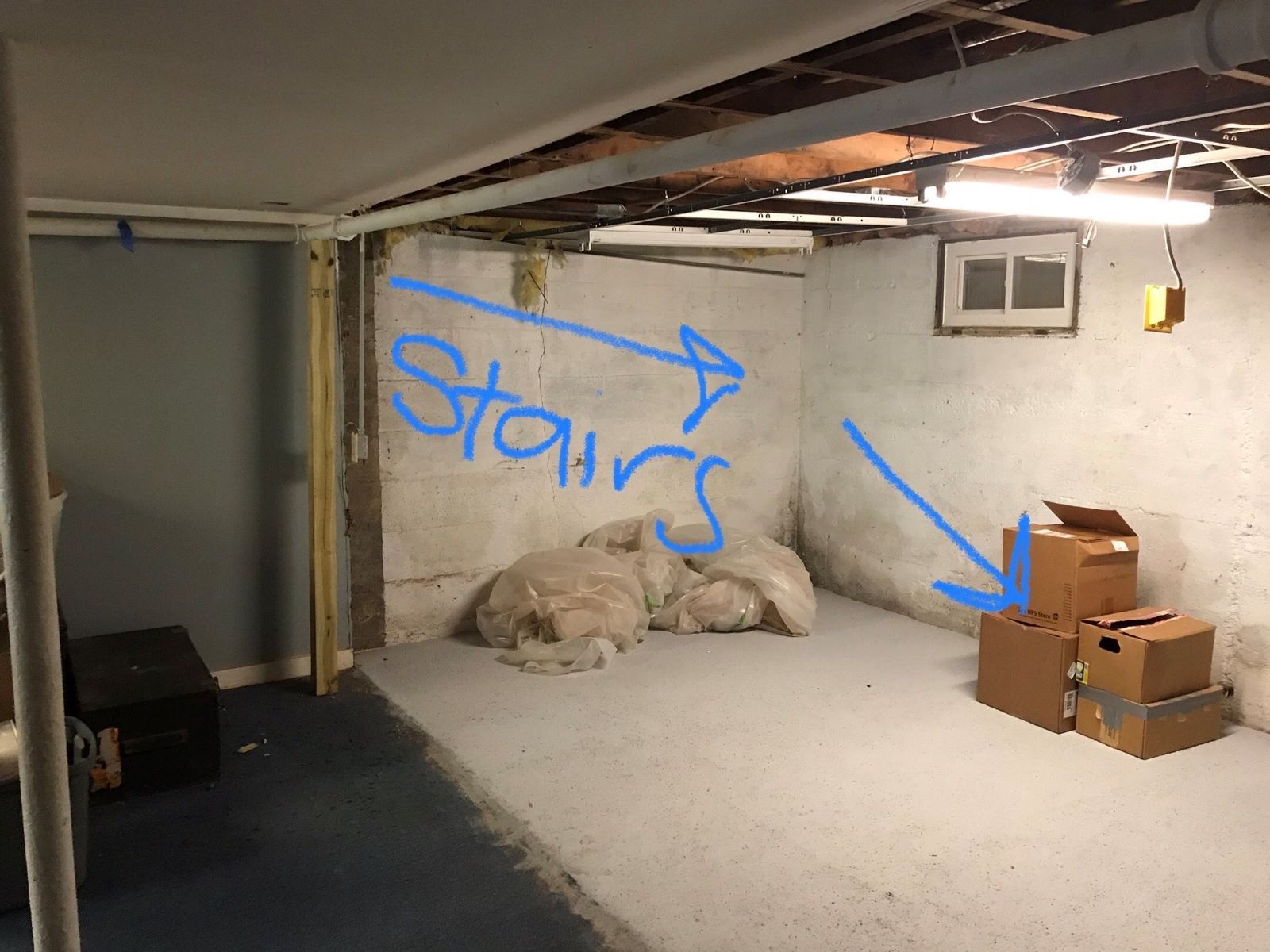 A basement with a blue arrow pointing to the stairs