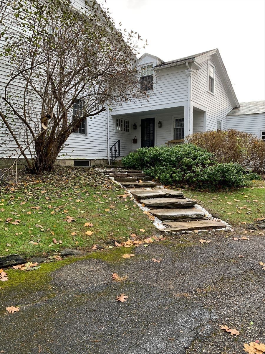 A white house with a stone walkway leading to the front door.