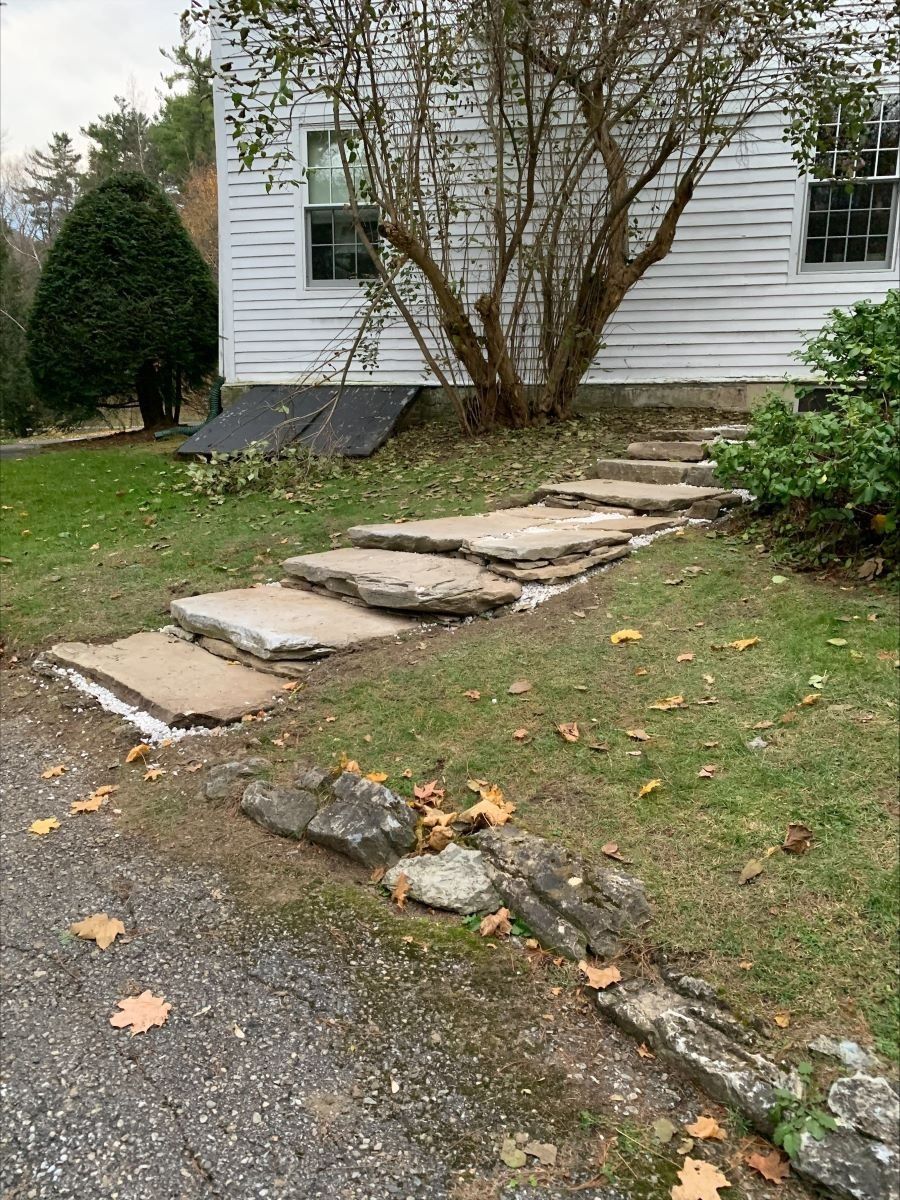 A stone walkway leading to a white house.