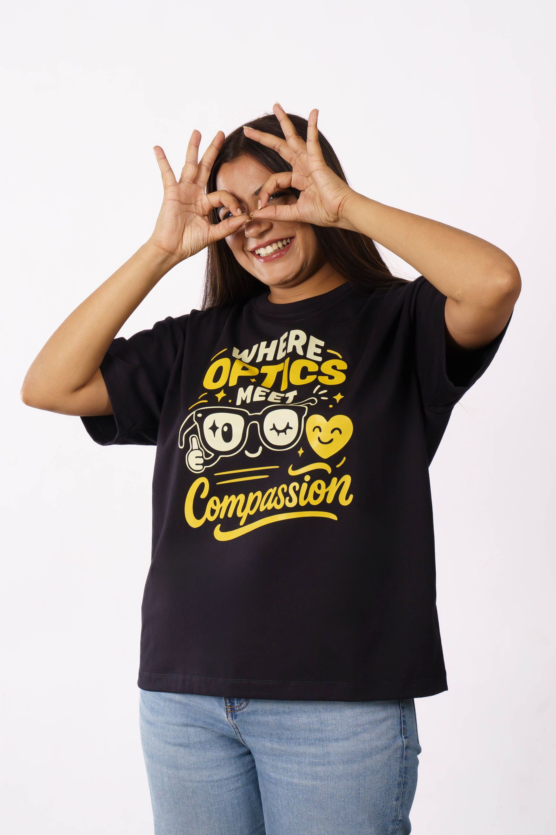 Smiling person in a black graphic T-shirt and jeans posing playfully against a white background