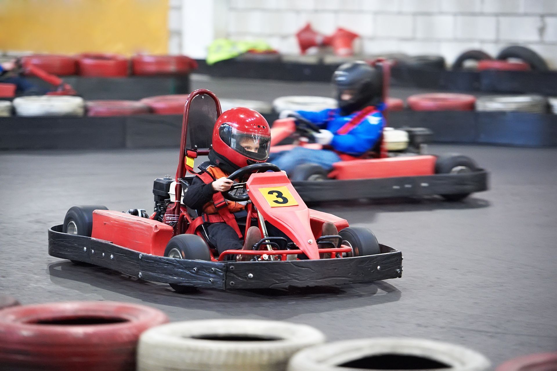 Two people are riding go karts on a track.