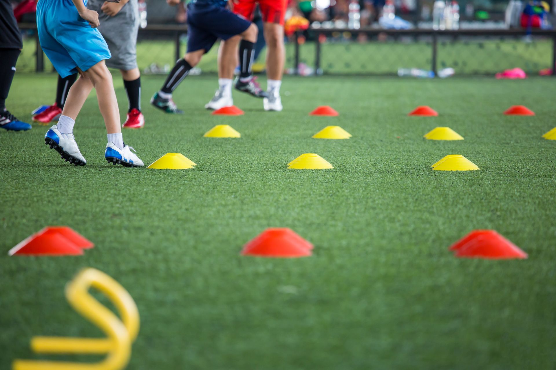 Children running agility drills with colored cones on a sports field