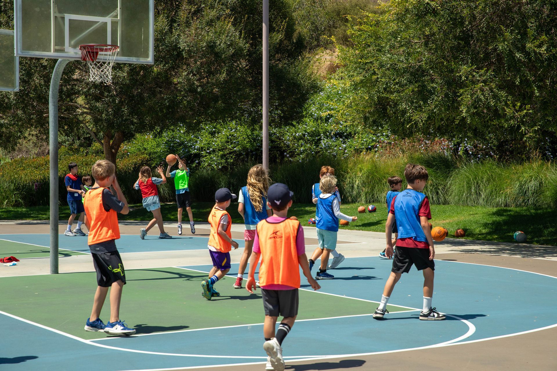Two children playing basketball indoors, one dribbling while another defends, with spectators in the background