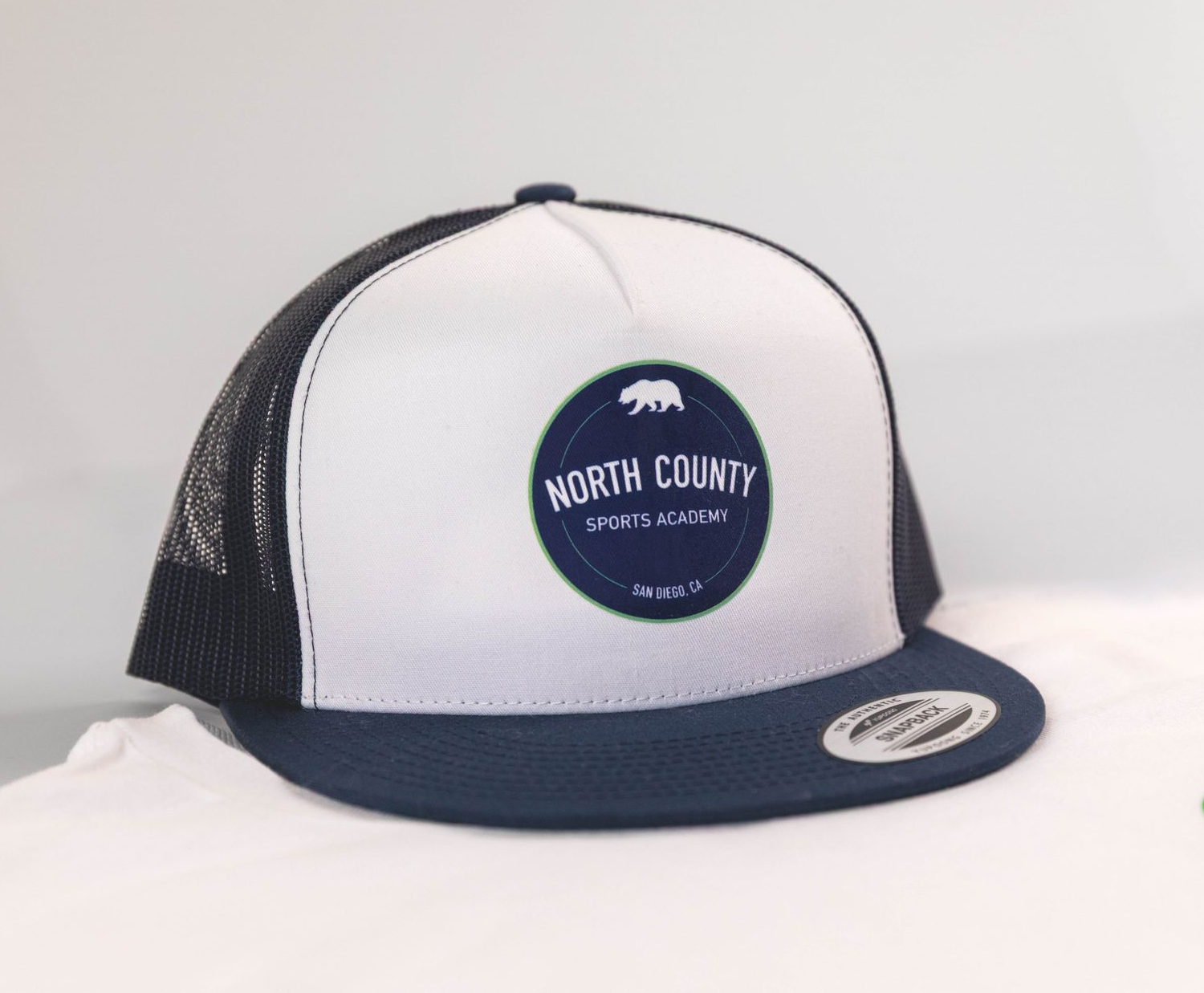 White and navy trucker cap with circular logo on a white background