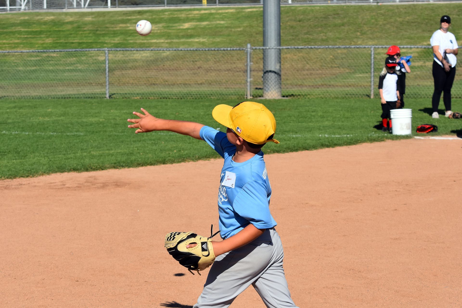 Baseball player catching a ball in front of a goal on a grassy field