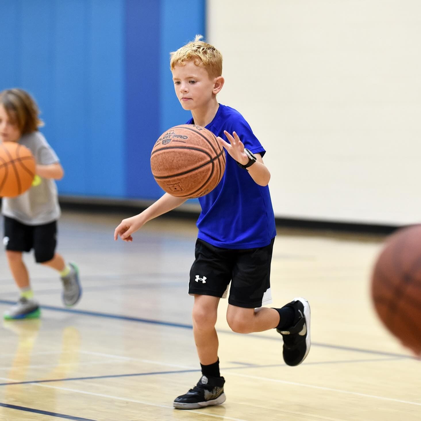 Boy dribbling a basketball in a gym during practice