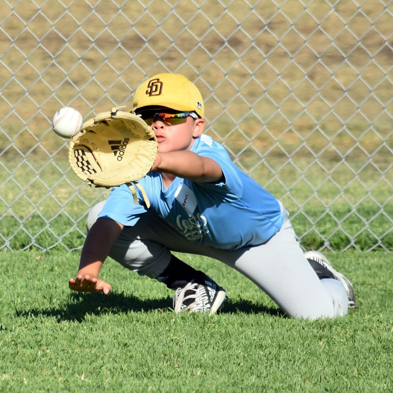 Baseball coach instructing a child batter at batting practice behind a net