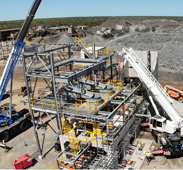 Heavy industrial machinery and steel framework at a construction site, with cranes and conveyor equipment on rocky terrain. — Custom Steel Fab in Bohle, QLD