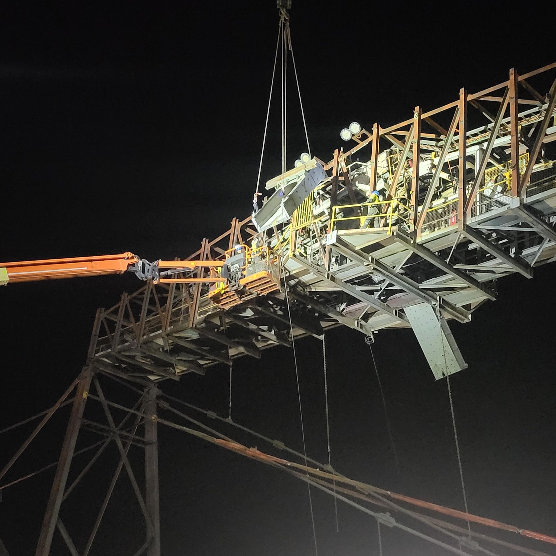 A Large Structure Is Being Lifted By A Crane At Night — Custom Steel Fab in Garbutt, QLD