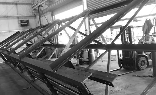 A Forklift Is Moving a Large Metal Structure in A Black and White Photo — Custom Steel Fab in Garbutt, QLD