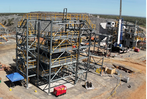 Steel construction frame at an industrial worksite with cranes, equipment, and dirt roads under a clear sky — Custom Steel Fab in Garbutt, QLD