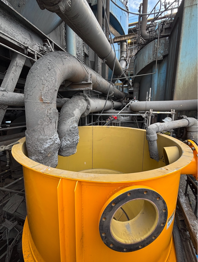 Yellow Industrial Container Beneath Large Gray Pipes in a Factory Setting — Custom Steel Fab in Bohle, QLD