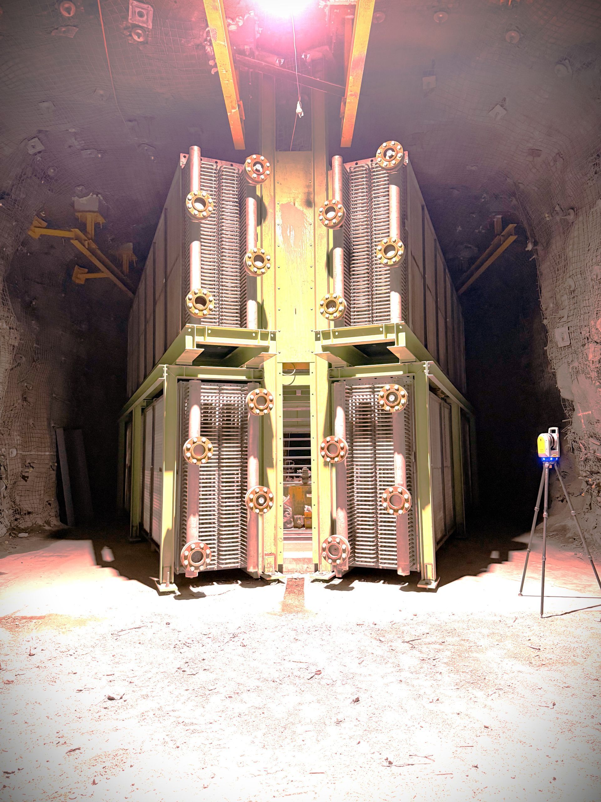 Industrial Machine With Stacked Metal Racks Inside a Dim Tunnel, Brightly Lit From Above — Custom Steel Fab in Bohle, QLD