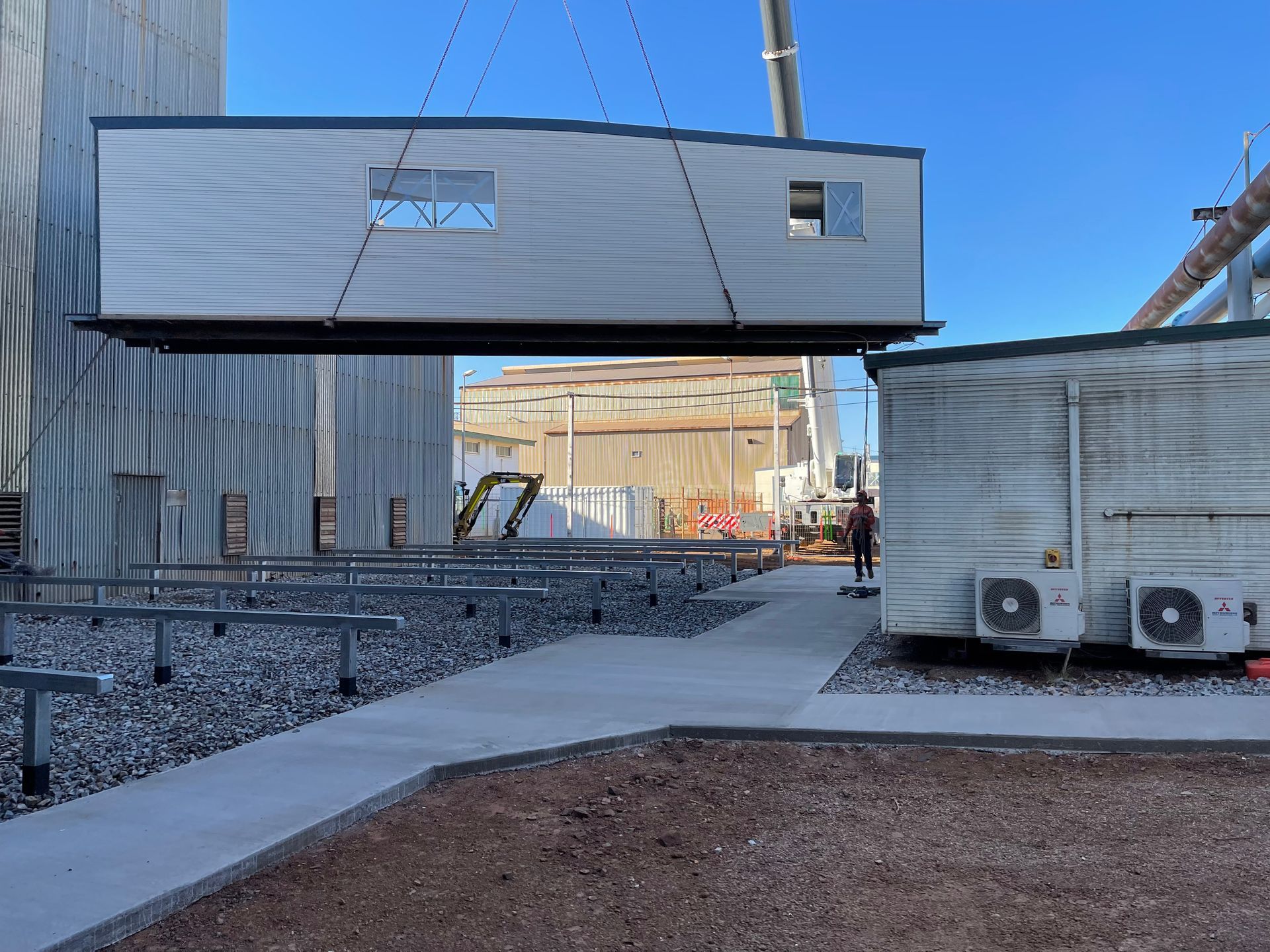 Suspended modular building section being lifted at an industrial construction site
