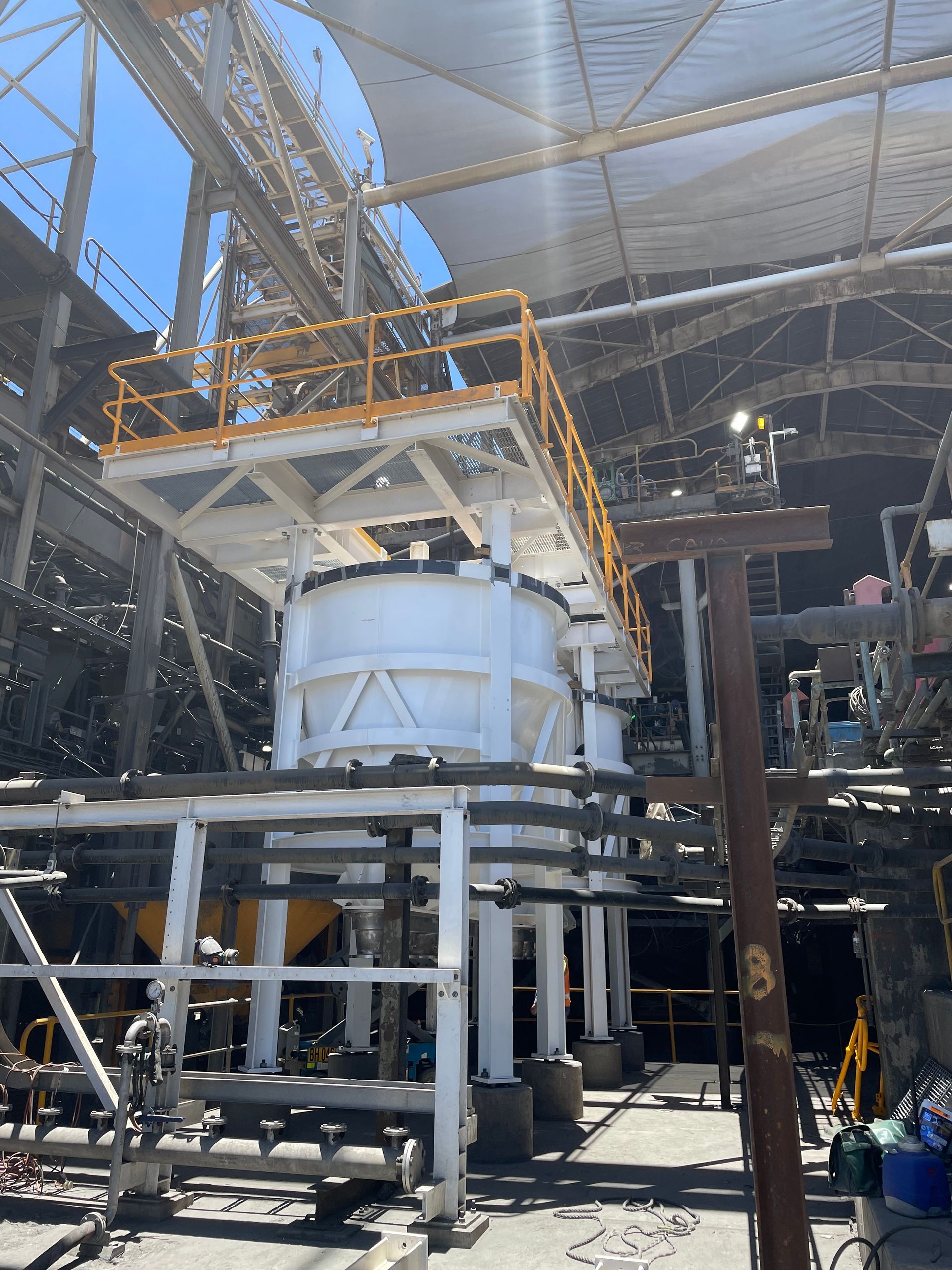 Large industrial machine with scaffolding and pipes inside a factory or construction site