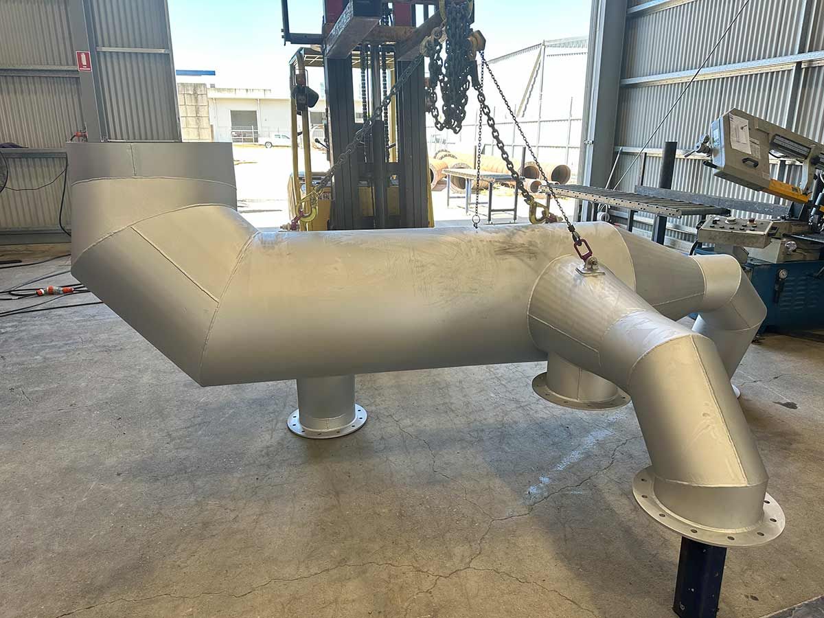 A Large Metal Pipe Is Sitting On The Floor In A Warehouse — Custom Steel Fab in Borroloola, NT