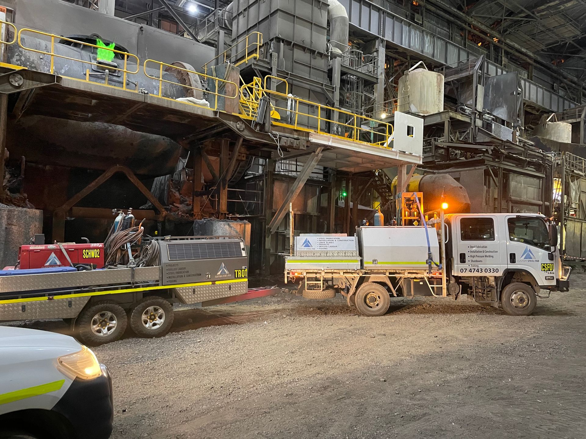 Mining Trucks Parked Beside an Industrial Processing Plant at Night — Custom Steel Fab in Bohle, QLD