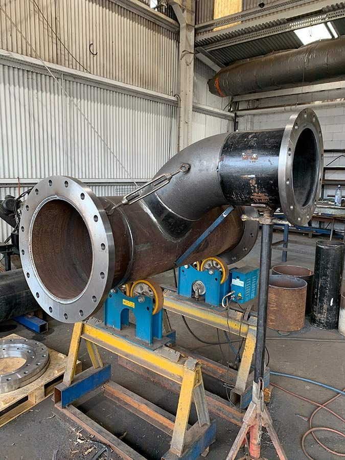 A Large Pipe Is Sitting On A Stand In A Factory — Custom Steel Fab in Julia Creek, QLD