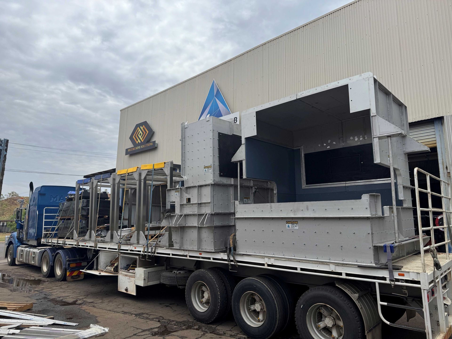 Industrial Truck Hauling Large Metal Machinery Outside a Warehouse — Custom Steel Fab in Bohle, QLD