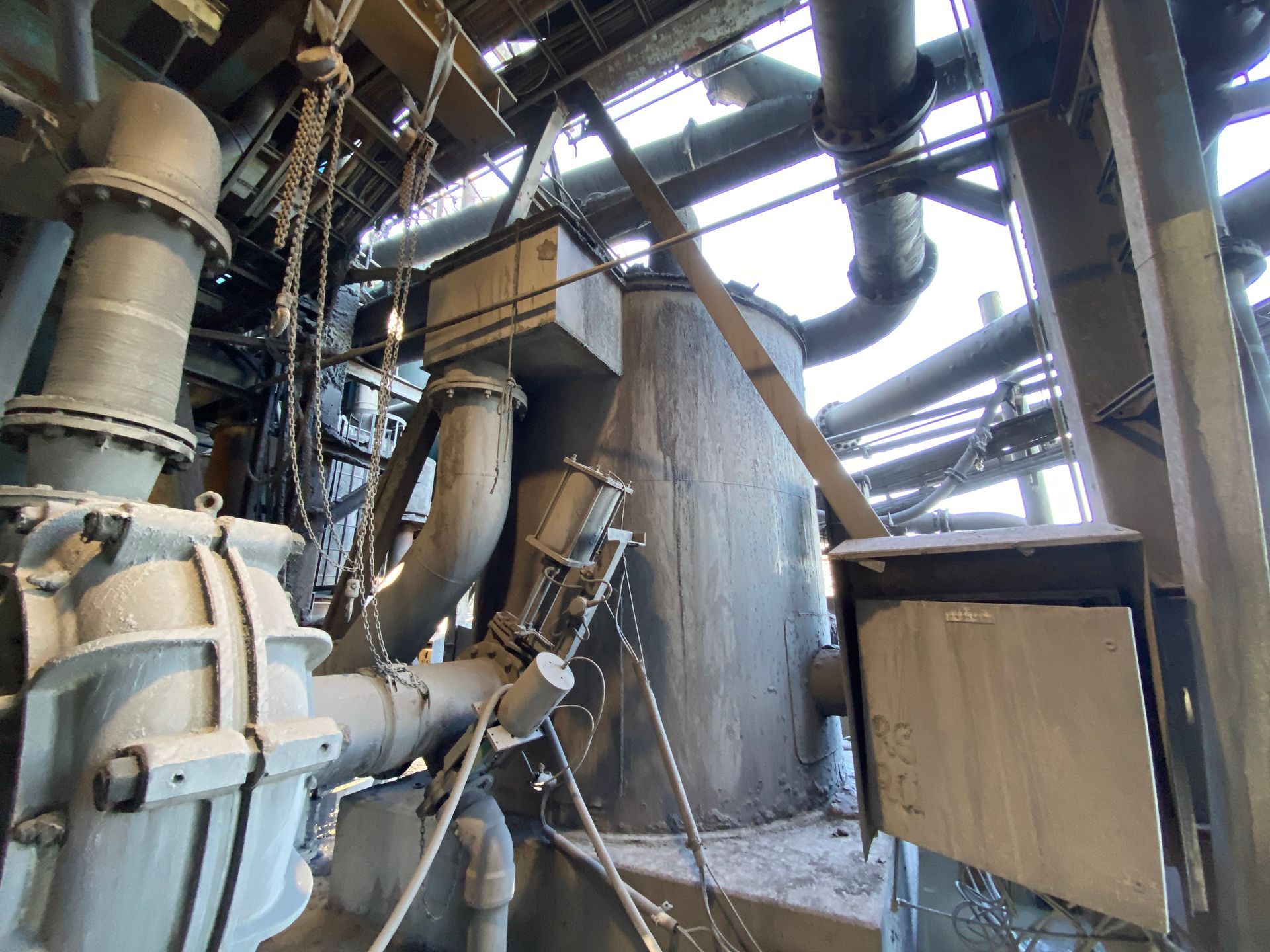 Dusty industrial machinery and piping inside a factory-like steel structure