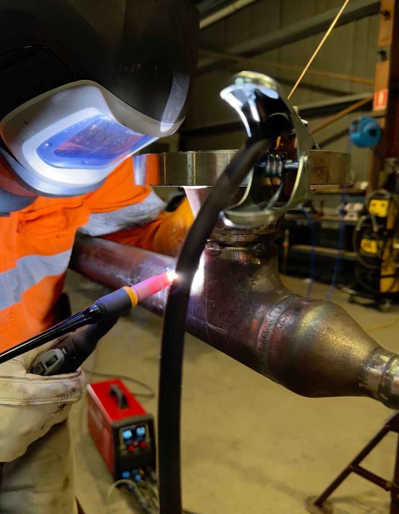 A Man Wearing A Welding Mask Is Welding A Piece Of Metal — Custom Steel Fab in Garbutt, QLD