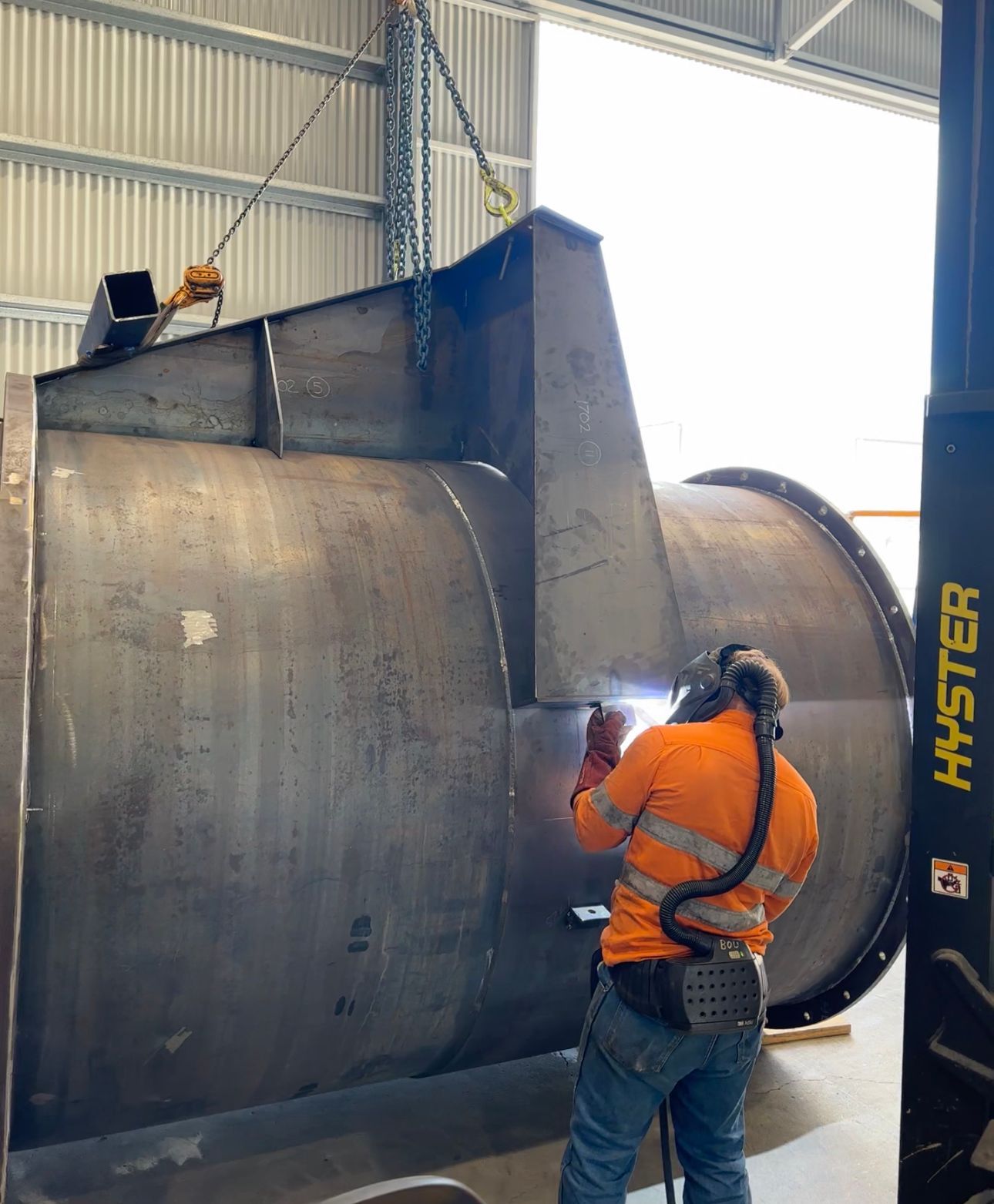 Worker in Orange Safety Gear Welding a Large Metal Structure — Custom Steel Fab in Bohle, QLD