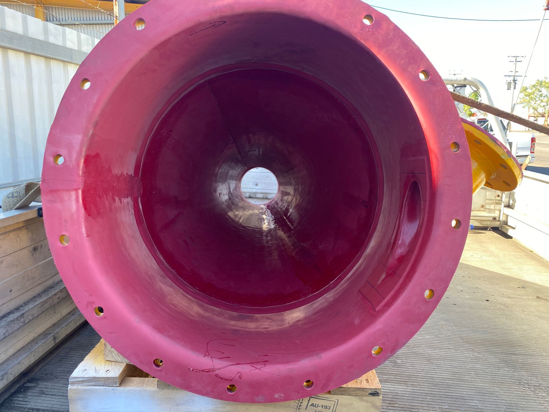 A Large Red Pipe With A Hole In The Middle Is Sitting On Top Of A Wooden Pallet — Custom Steel Fab in Garbutt, QLD