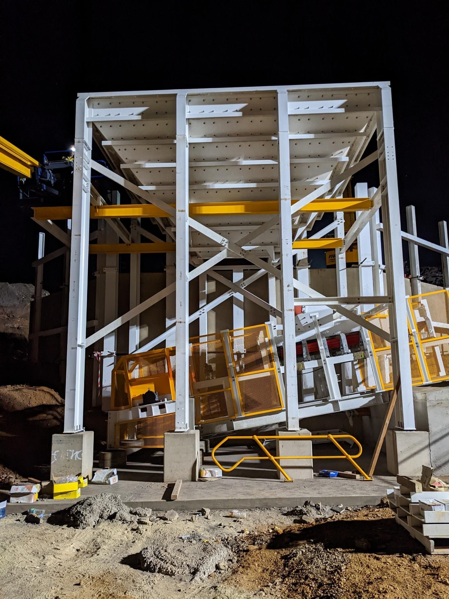 Industrial Machine Inside a White Metal Frame at a Construction Site, Lit at Night — Custom Steel Fab in Bohle, QLD