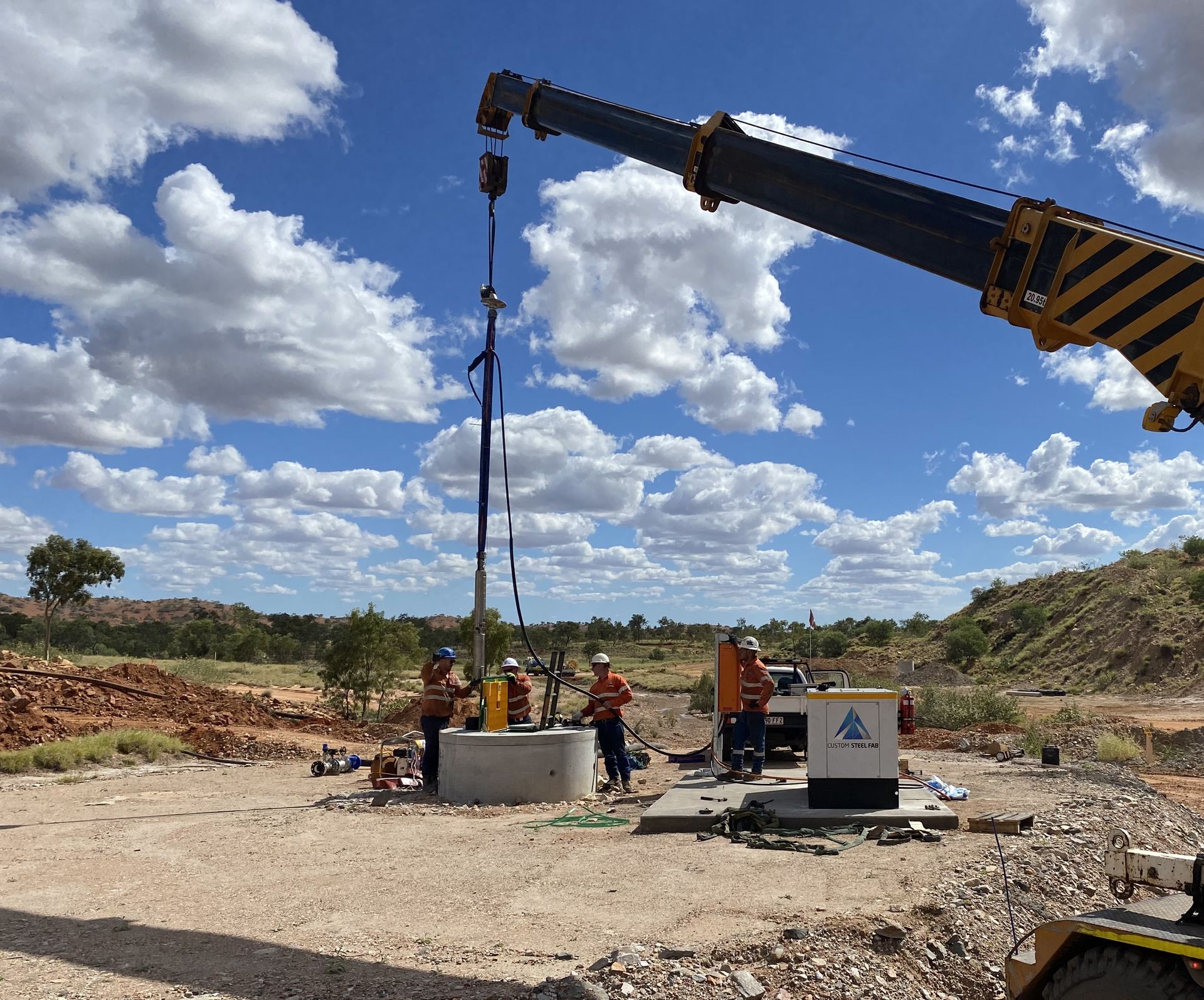 Construction Crew Operating a Crane at a Worksite Under a Cloudy Sky — Custom Steel Fab in Bohle, QLD