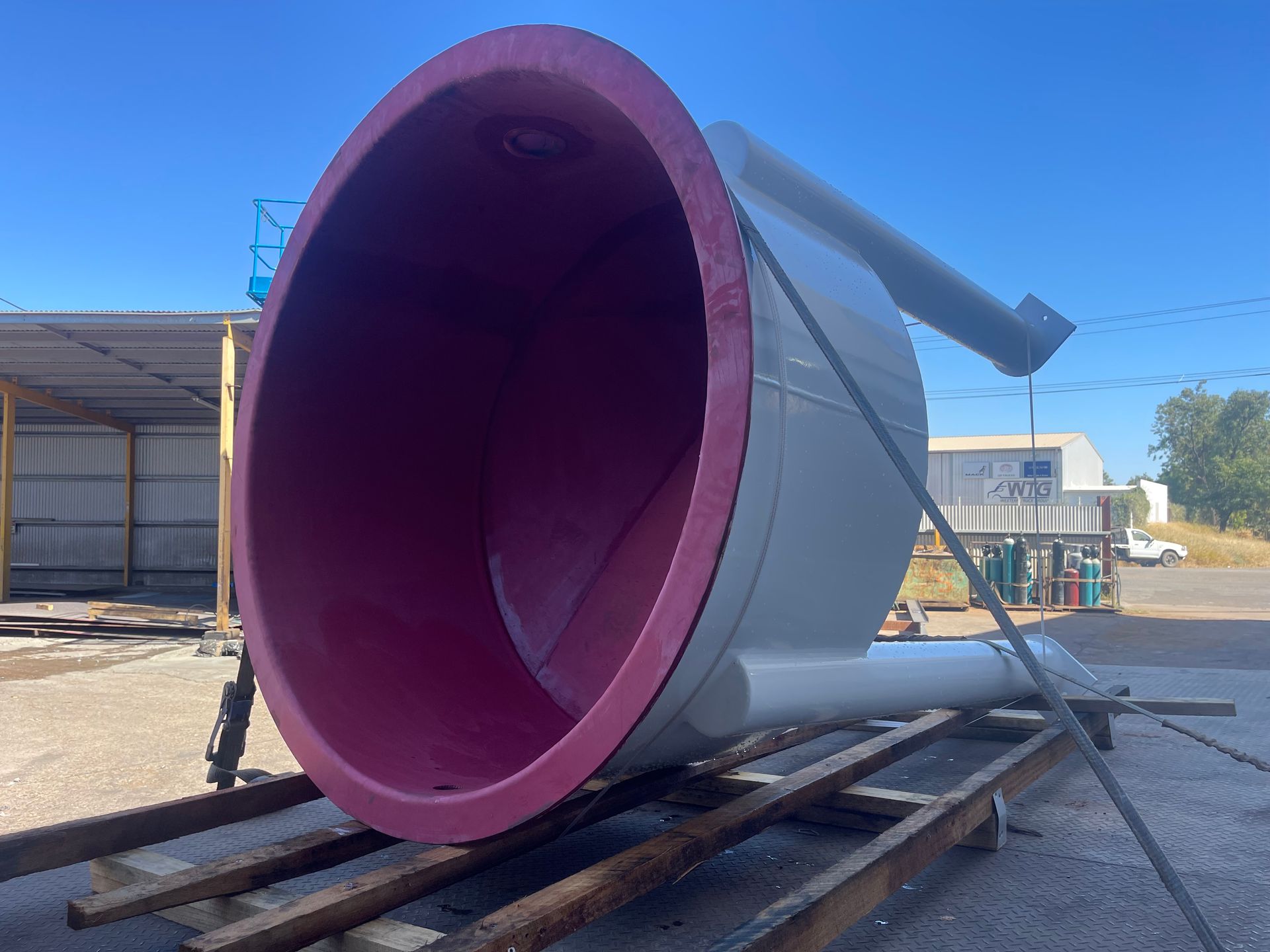 A Large White And Red Pipe Is Sitting On A Wooden Pallet — Custom Steel Fab in Garbutt, QLD