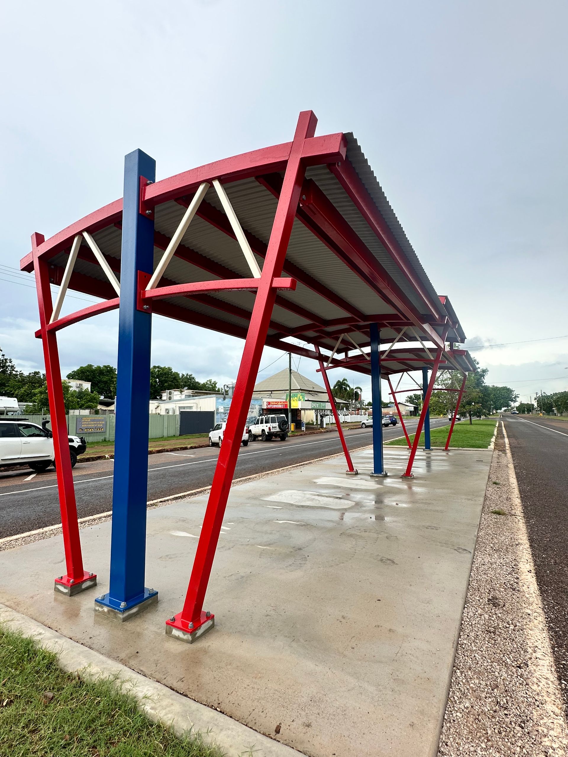 Red-and-blue Solar Canopy Shelter Over a Wet Pavement — Custom Steel Fab in Bohle, QLD