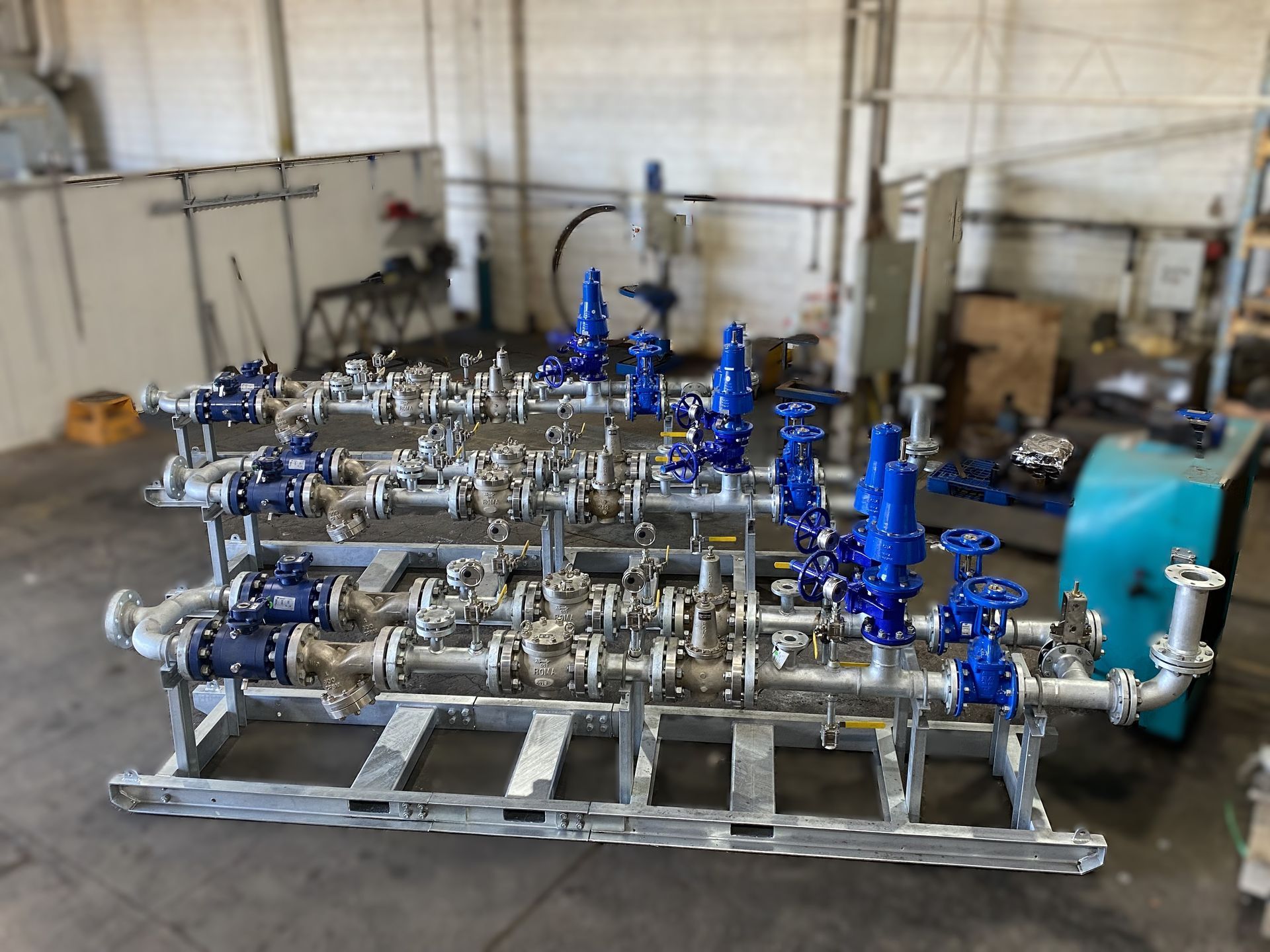 Industrial Piping Assembly With Blue Valves and Metal Frames Inside a Workshop — Custom Steel Fab in Bohle, QLD
