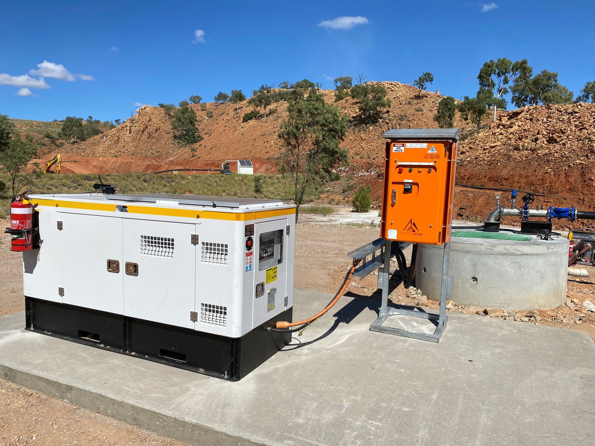 White Generator Beside Orange Utility Box on a Concrete Pad — Custom Steel Fab in Bohle, QLD