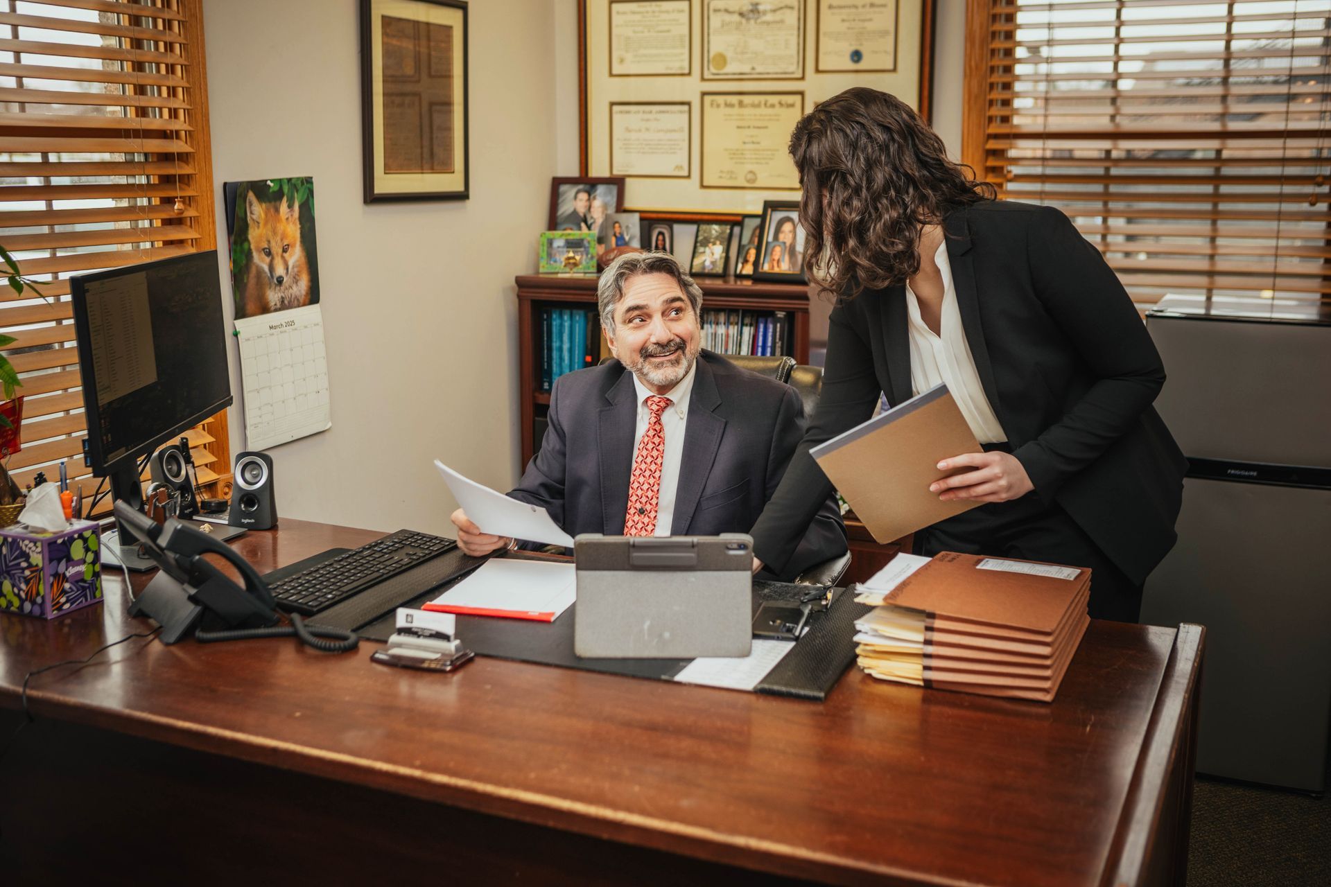 A man and a woman are sitting at a desk in an office.