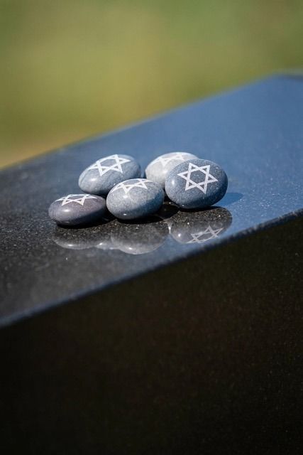 Small stones painted with Stars of David on a dark surface outdoors