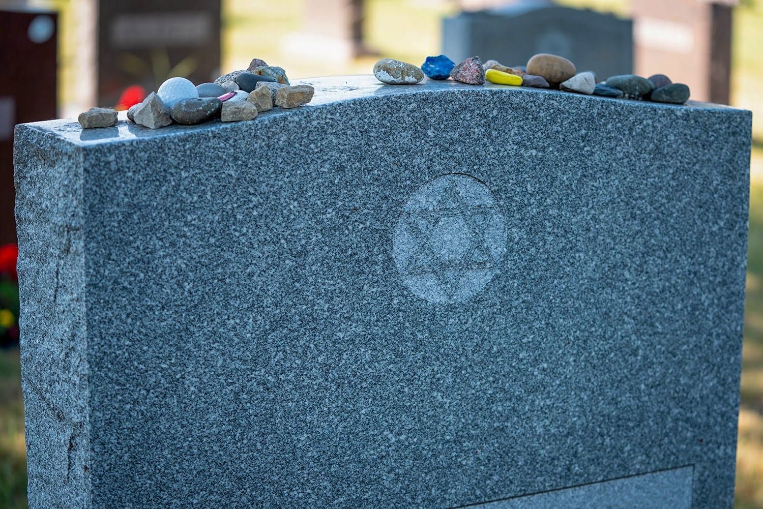 Gray granite memorial stone with small pebbles on top outdoors