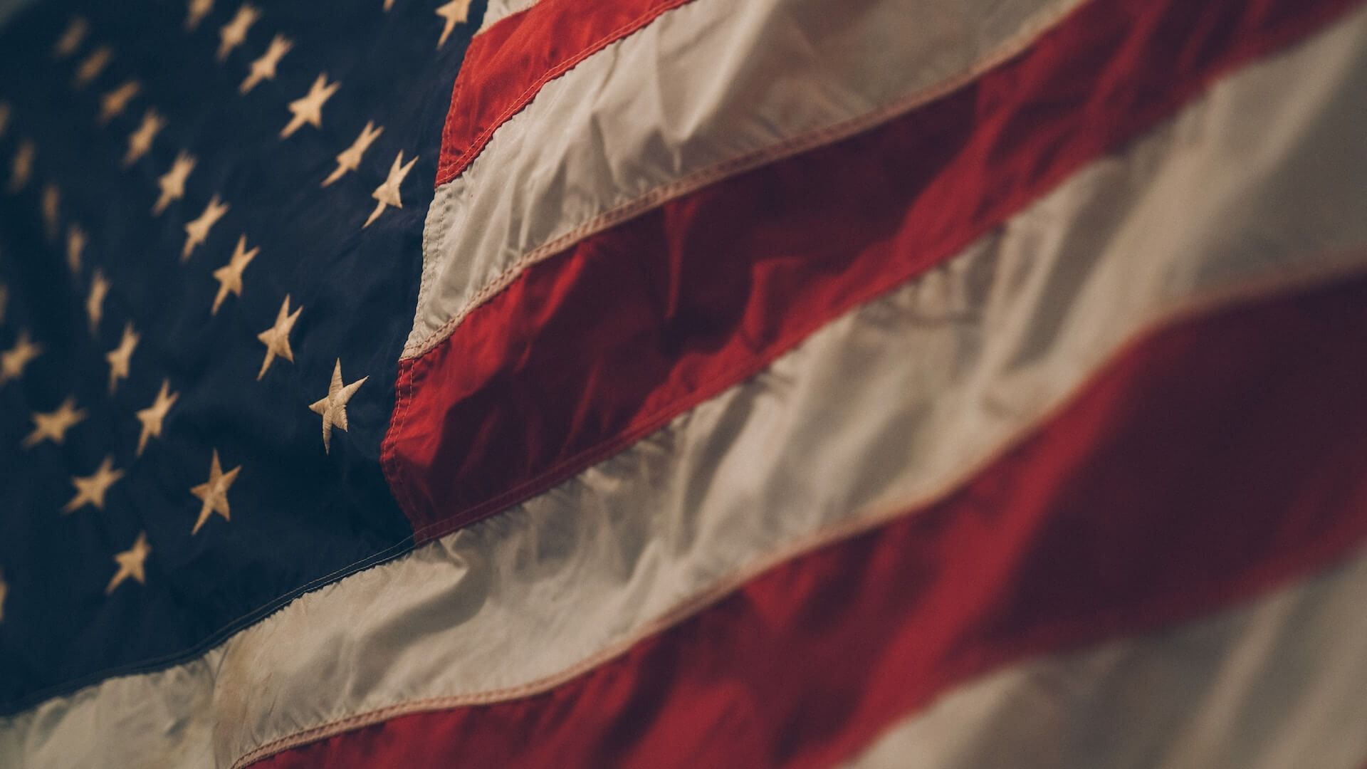 Close-up of the American flag waving, with stars and red-and-white stripes visible.