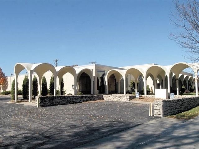 White arched building with colonnade and stone walls under a clear blue sky