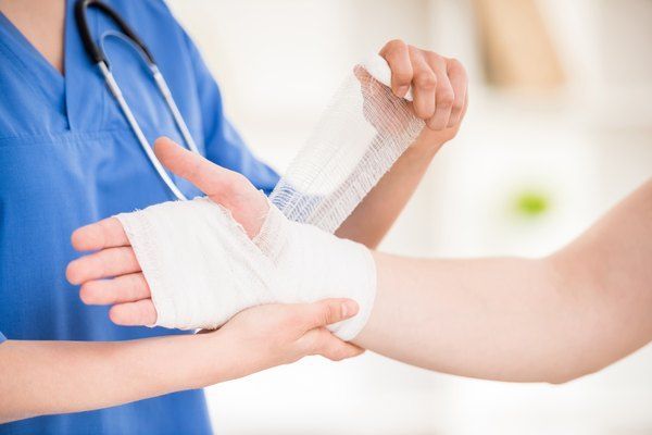 Una enfermera está envolviendo el brazo de un paciente con un vendaje.